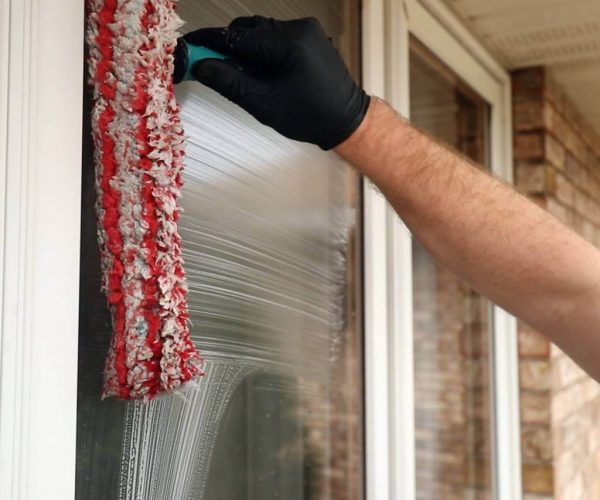 professional cleaning expert cleaning window with red brush